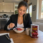 Professional woman eating healthy yogurt bowl with SNAFRE fruit crumbles at desk